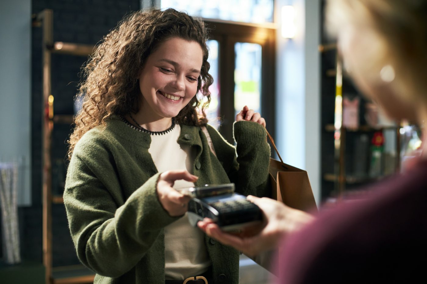 A customer paying at a shop counter with a card terminal