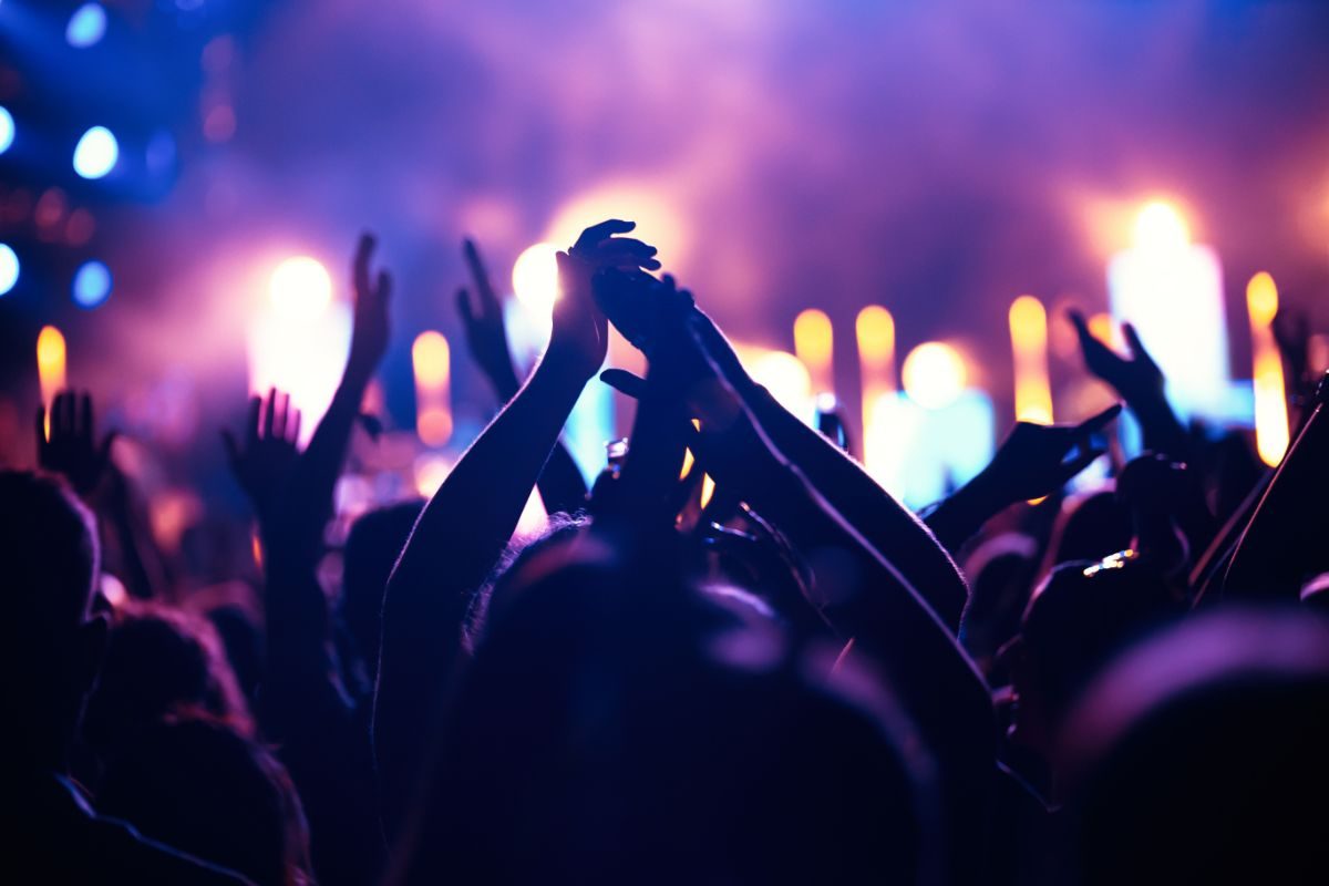 Multitud con las manos en alto en un concierto nocturno